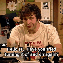 A white guy picking a phone up, text reads ‘Hello IT, have you tried turning it off and on again’